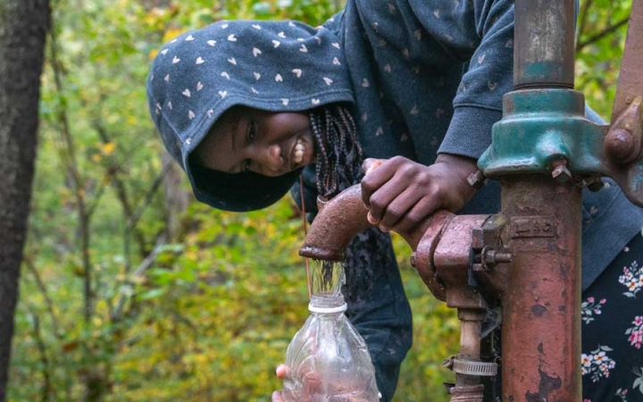 a student fills up a water bottle on a canoeing trip with outward bound